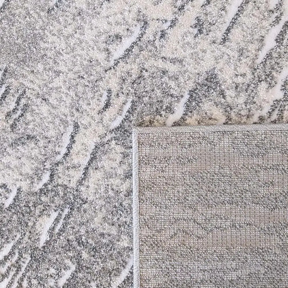 Tepe Enigma 03 grått teppe, nærbilde av marmormønster og kantet hjørne med synlig bakside.