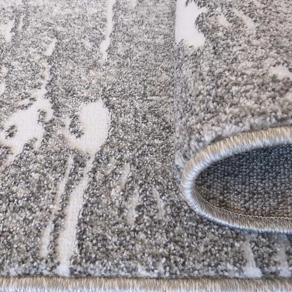 Tepe Enigma grått teppe, nærbilde av tykk tekstur, abstrakt mønster og oppbrettet kant med synlige detaljer.