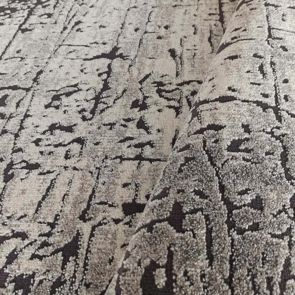 Tepe Enigma teppe i grått, nærbilde av loddent abstrakt mønster og oppbrettet kant som fremhever teksturen.