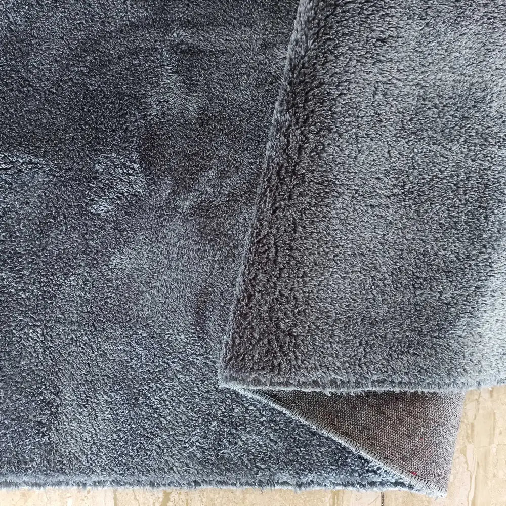 Tepe Enzo antracit teppe 80 x 300 cm, nærbilde av teksturen og brettet hjørne som viser undersiden.