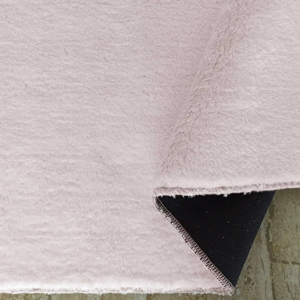 Tepe Enzo Pudder, nærbilde av lys rosa loddent teppe med oppbrettet hjørne og synlig mørk underside.