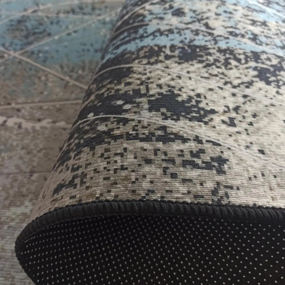 Tepe hotell- og restaurantteppe, detalj av rullet kant med antiskli-prikker og blått, beige og svart mønster.