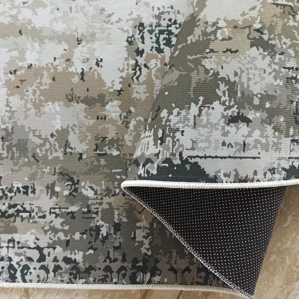 Tepe for utesteder, grått og grønt kamuflasjeteppe, detalj av hjørne med synlige hvite gummiprikker under.