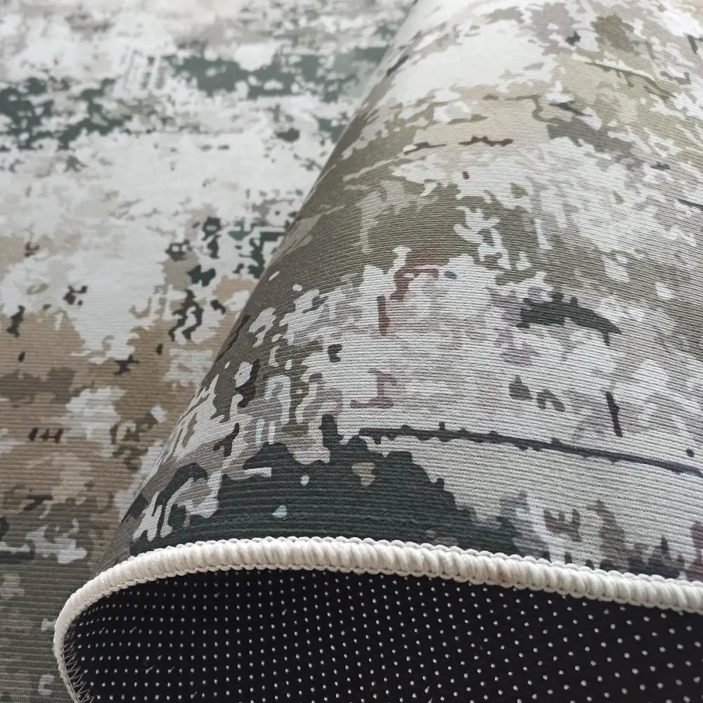 Teppe for utesteder, nærbilde av grønt og beige abstrakt mønster, antiskli-bakside og hvit kant.