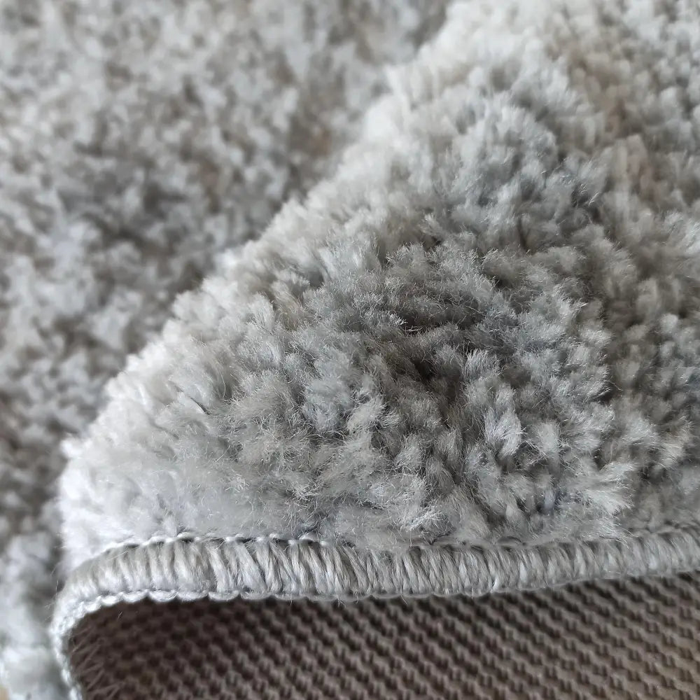 Tepe grå kamel rundt teppe 140 cm, nærbilde som viser myk loddent overflate og vevd underside i detalj.