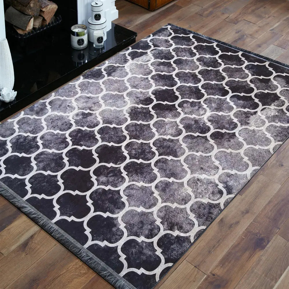 Tepe Horeca svart teppe med lyst marokkansk mønster, skråvinkel på tregulv ved peis og dekorative lys.