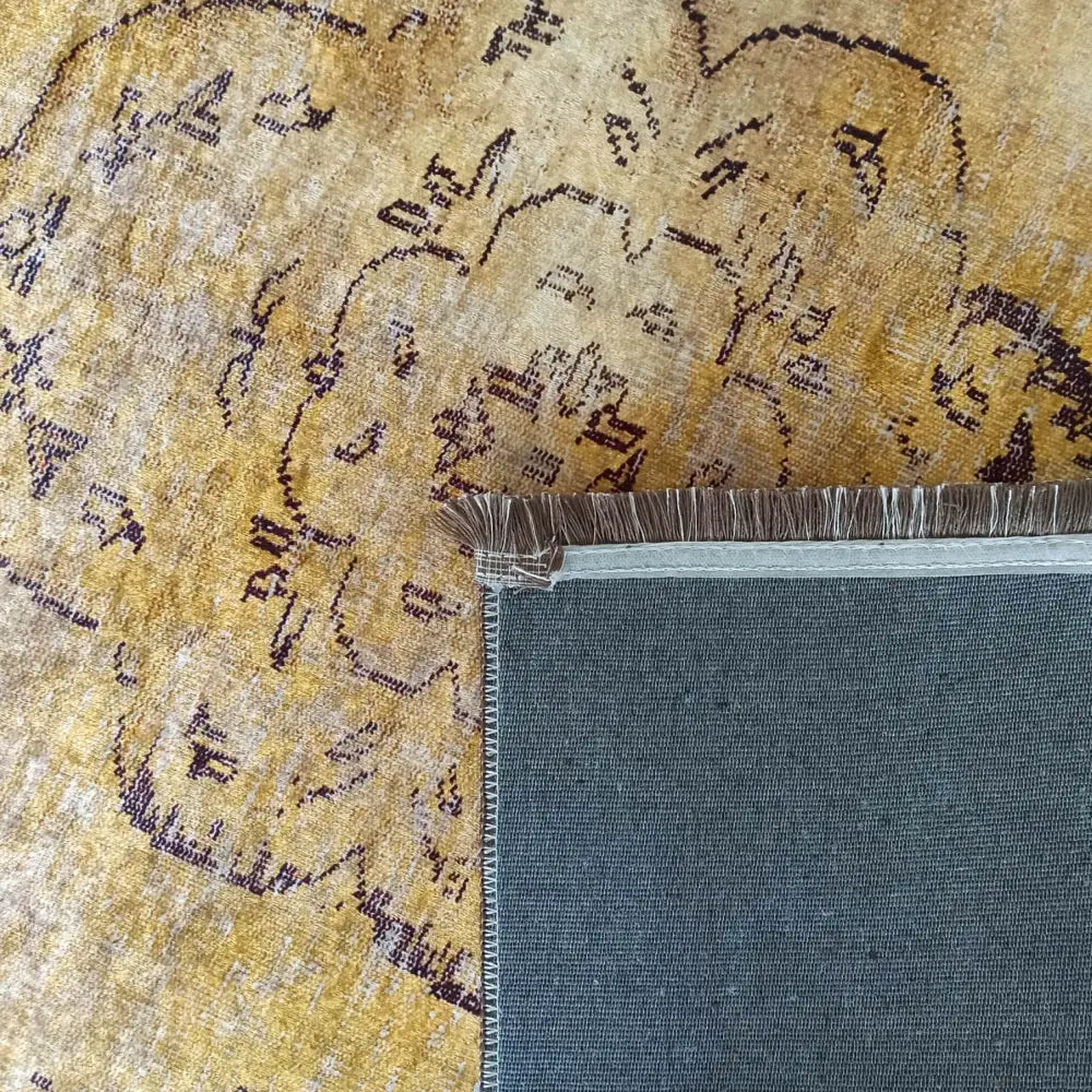 Tepe Horeca-Ny teppe, bakside i grått med frynser og synlig orientalsk gul-lilla mønster på forsiden.