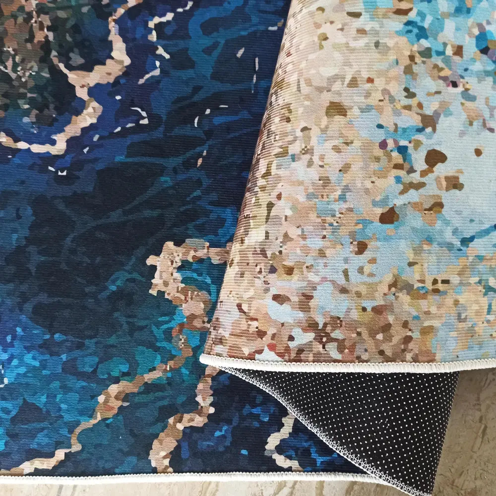 Tepe Horeca-Nytt teppe i blått og beige mønster, nærbilde av brettet hjørne som viser antiskli bakside.