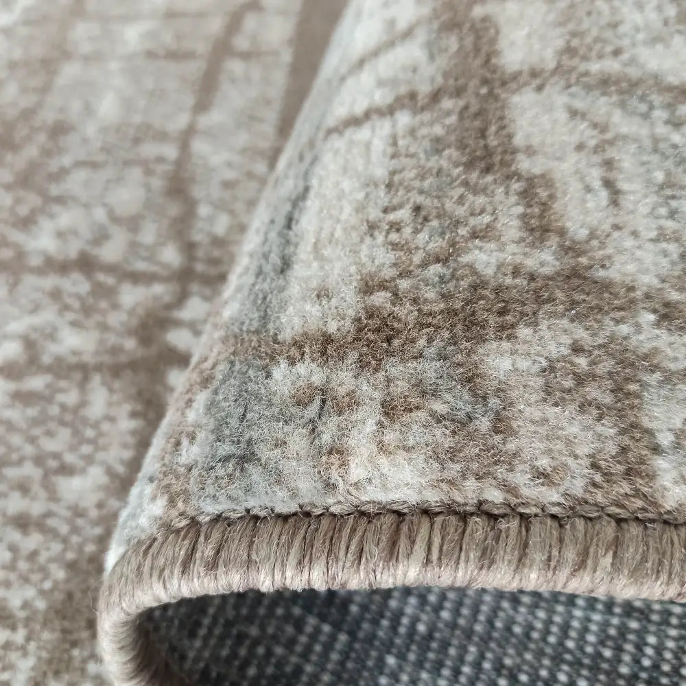 Tepe Roxanne teppe i beige og brune nyanser, detaljert sidebilde som fremhever tykk kant og struktur.