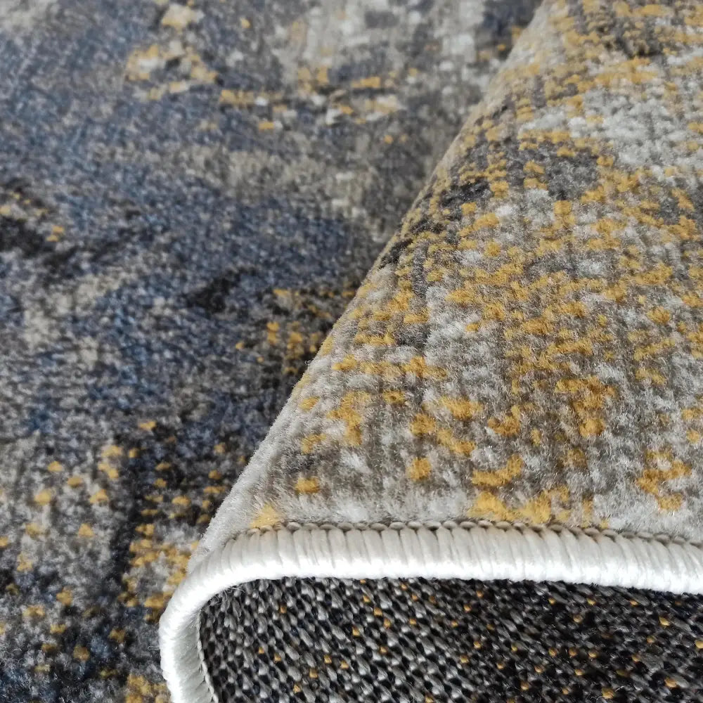 Tepe Lara teppe i blå, grå og okergult, nærbilde av tekstur og hvit kant på kortsiden.