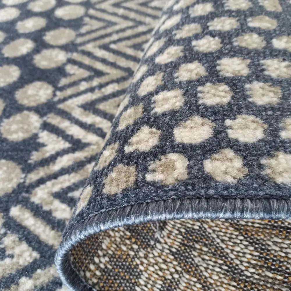 Tepe Lara teppe 200 x 290 cm, nærbilde som fremhever mørkegrå bunn, beige prikker og tydelig tekstur.