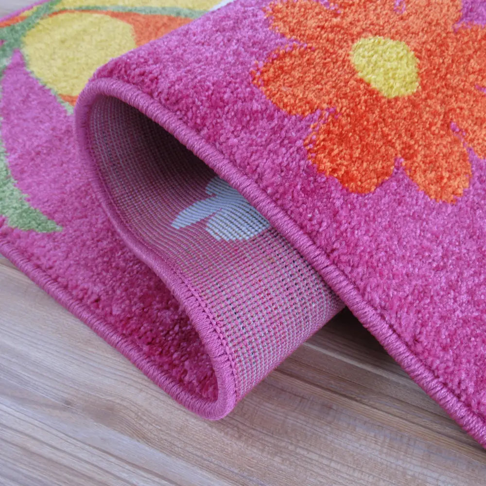 Tepe Lilla teppe, nærbilde av rosa overflate med oransje og gule blomster, viser vevet bakside.