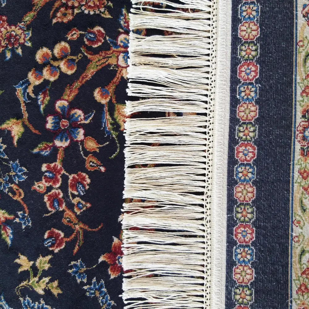 Tepe Luksuriøs Qum Silk teppe, nærbilde av marineblå bunn med blomster, dekorativ bord og lyse frynser.