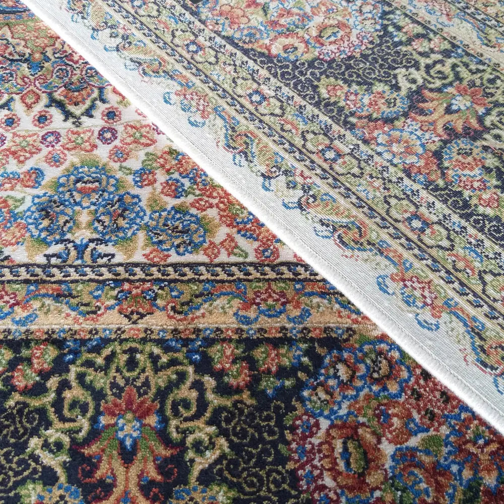 Tepe Luksuriøs Qum Silk teppe, nærbilde av hjørne som viser mønster og begge sider i blå og røde toner.