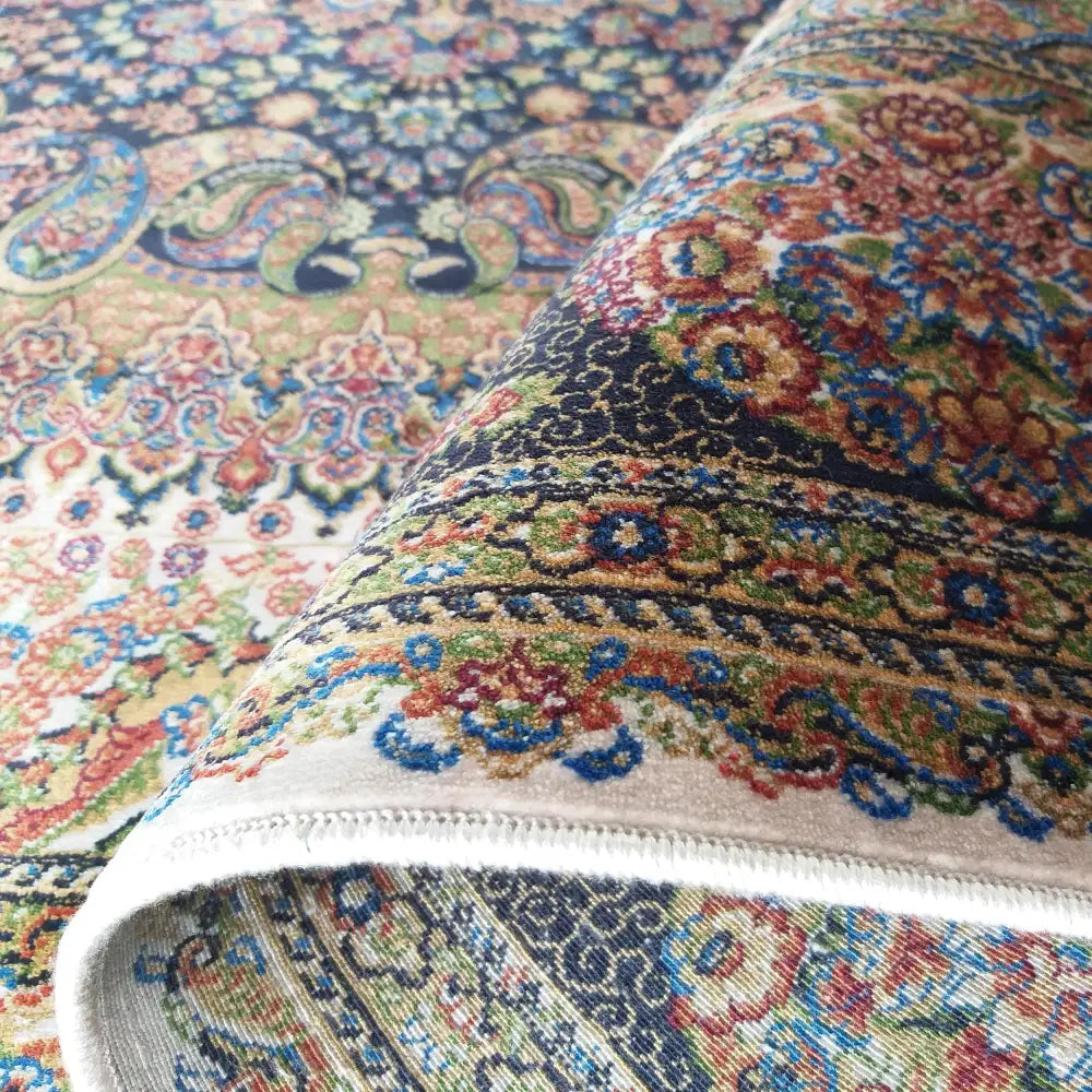 Tepe Luksuriøs Qum Silk teppe, nærbilde av hjørne brettet opp som viser tett vevd flerfarget mønster.