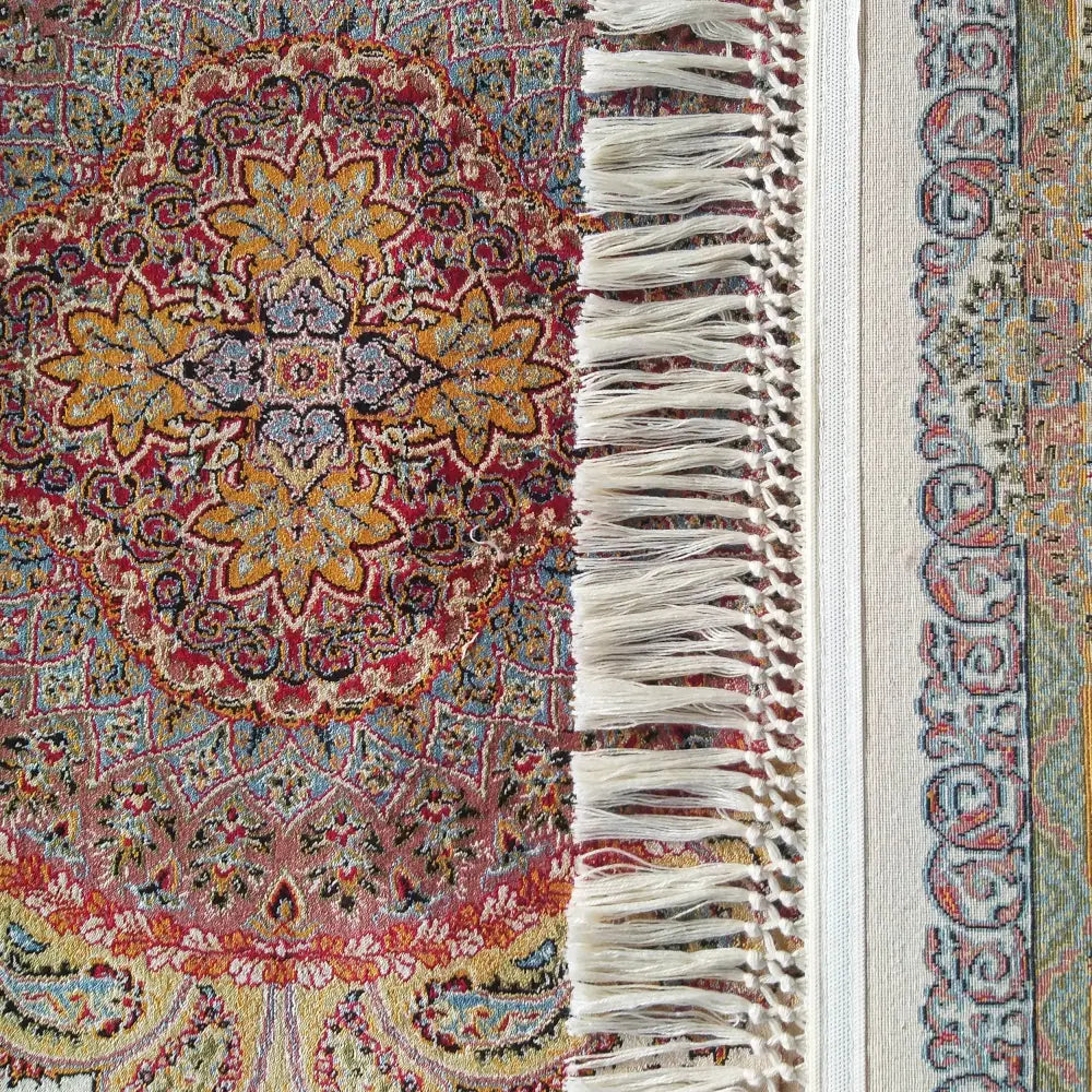 Tepe Luksuriøst Pers 03 teppe, nærbilde av orientalsk mønster i rødt, blått og gult med hvite frynser.