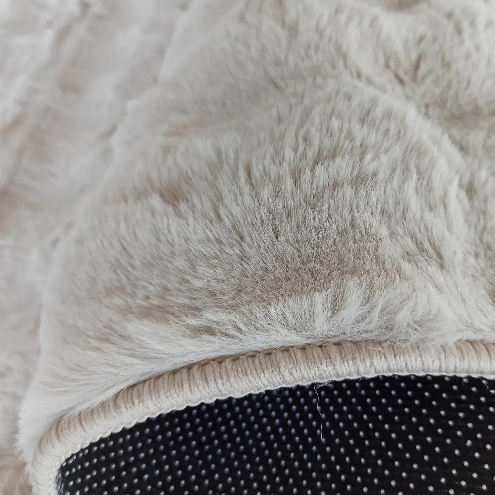 Tepe Merlin 3D Latte, nærbilde av beige kunstpels med sort, prikket bakside og markerte kanter.