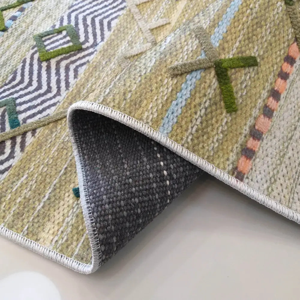 Tepe Moderne Hypnotik 05 teppe i lyse grønntoner, nærbilde med oppbrettet hjørne som viser undersiden.