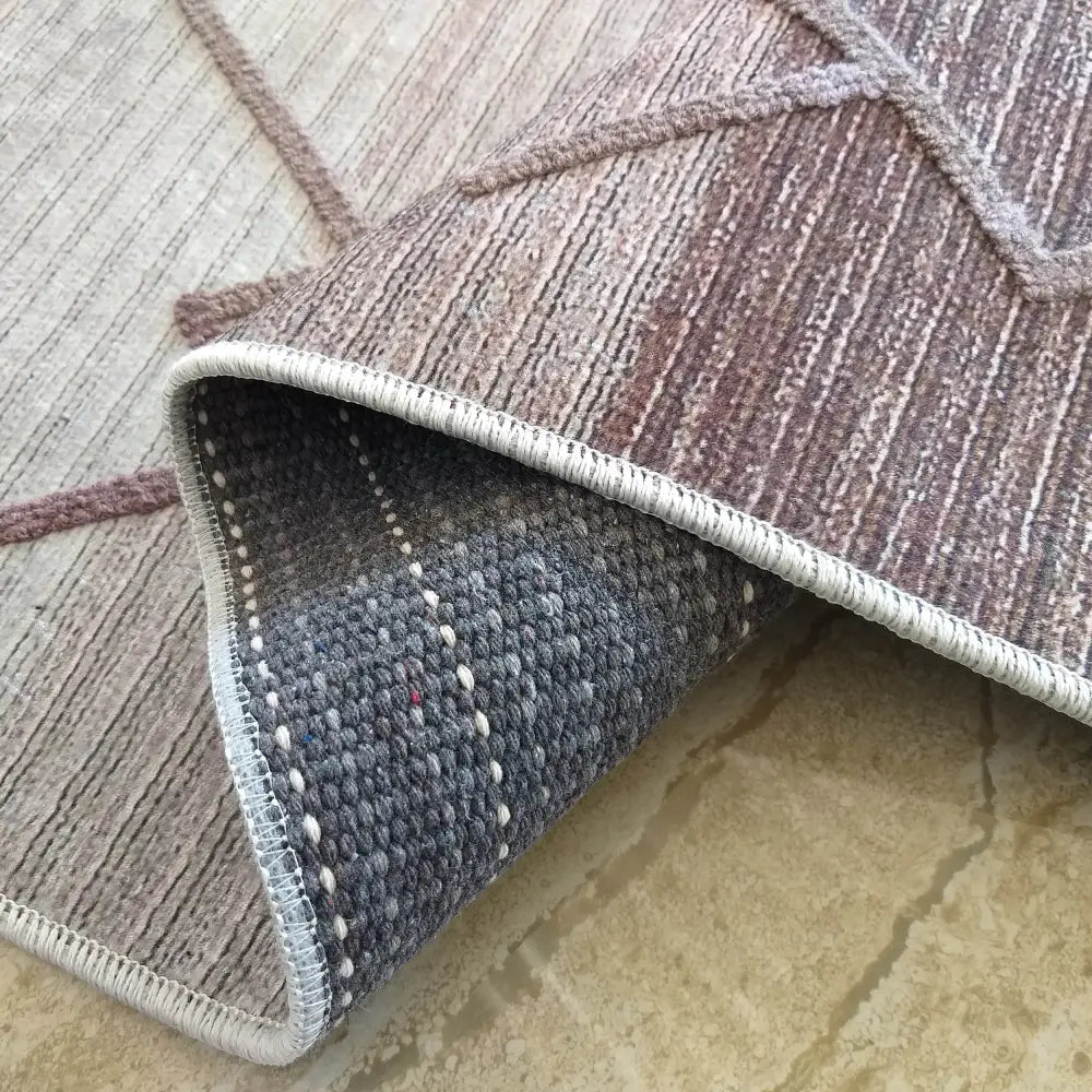 Tepe Moderne Hypnotik 06 teppe, nærbilde av hjørne brettet opp for å vise undersiden og kantsøm.