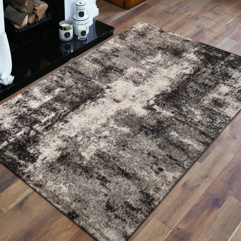 Tepe Moderne Teppanamero 05 teppe 160x220 cm, abstrakt mønster i gråtoner, skrått vist ved peis på tregulv.