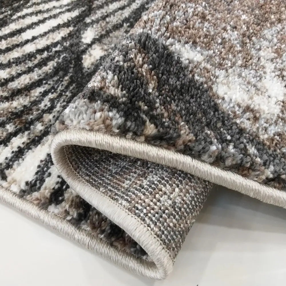 Tepe Moderne teppe i brun, detaljert nærbilde av kant med tettvevd luv og synlig tekstur i grå, beige og hvitt.