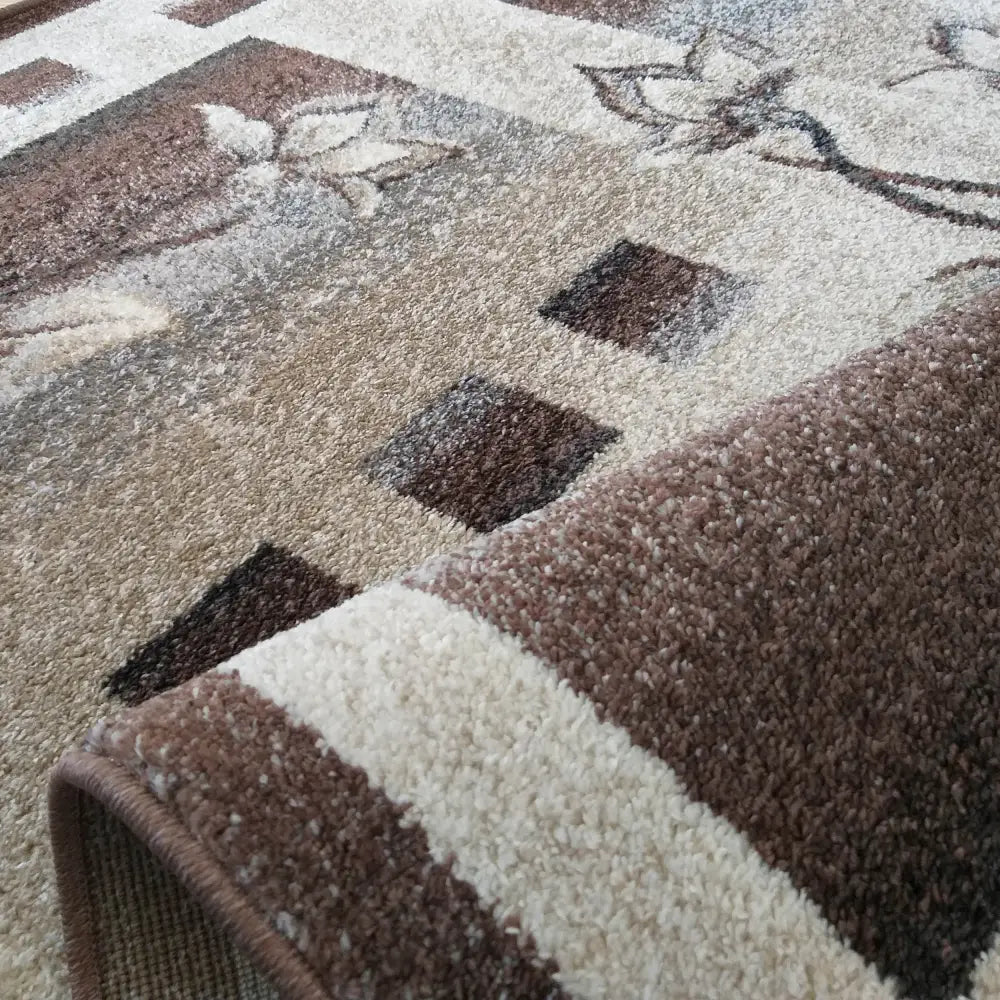 Tepe Otto 02 brun teppe, nærbilde av firkanter og bladmønster samt synlig tykk tekstur i brettet kant.