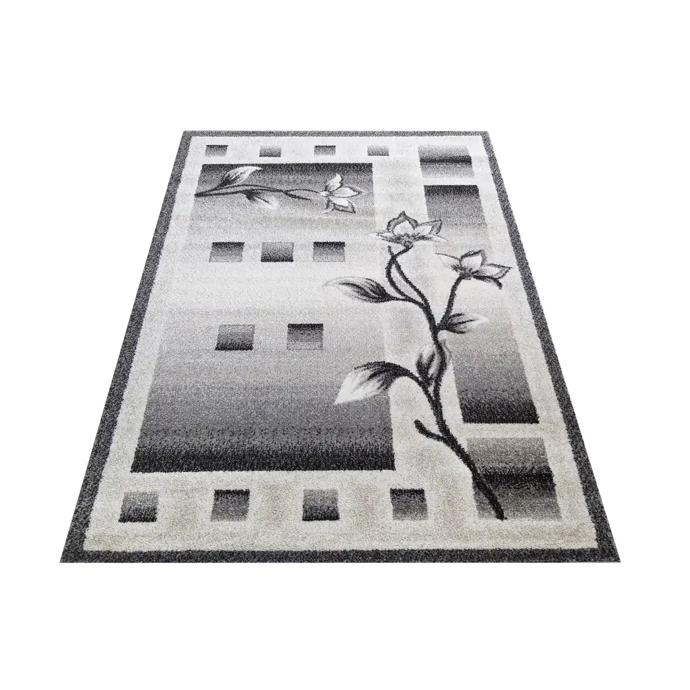Tepe Otto teppe i gråtoner, gradientmønster med blomster og firkanter, sett skrått fra oversiktsperspektiv.