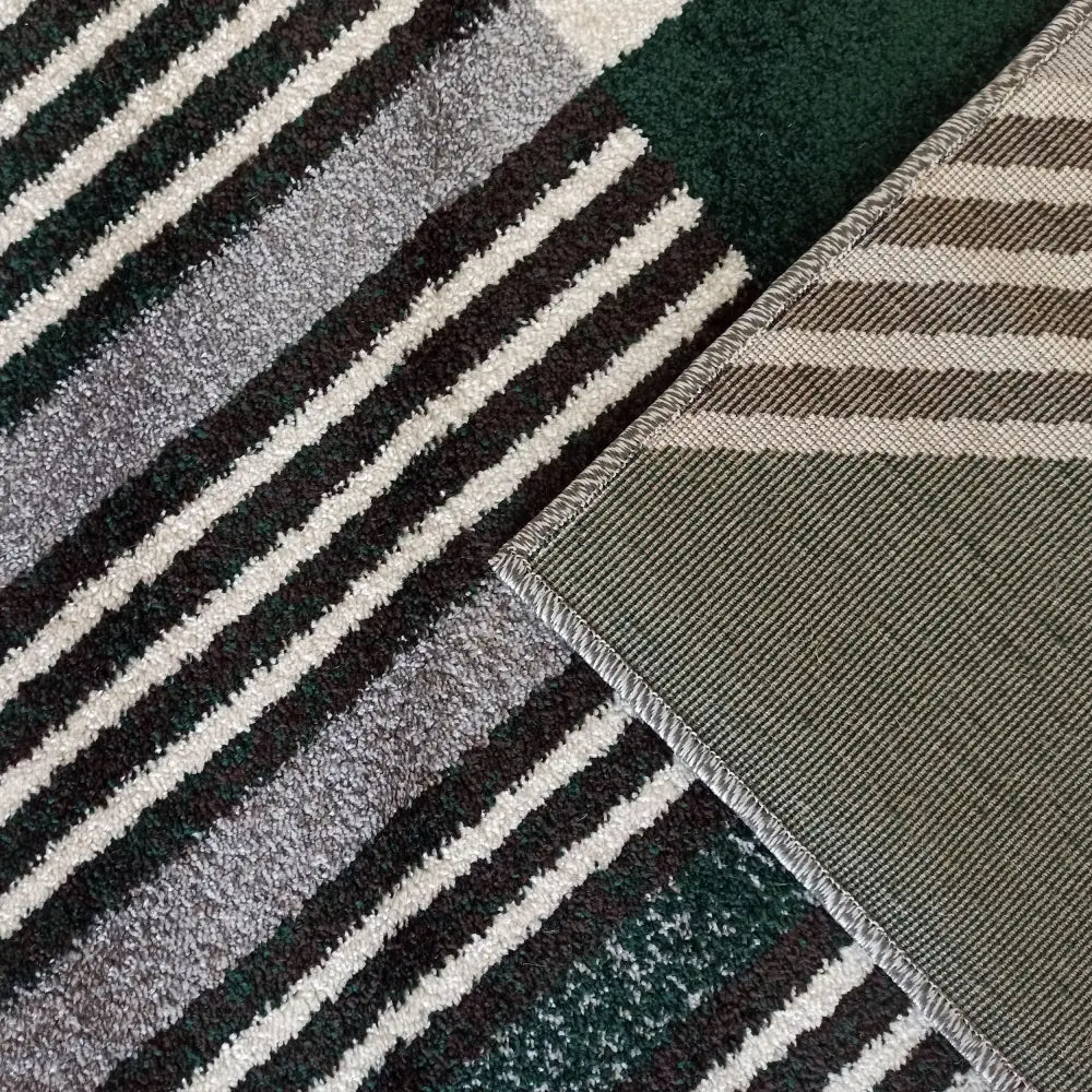 Tepe Otto teppe nærbilde, lodden grå overflate med hvite og mørkegrønne striper, synlig flatvevd bakside.