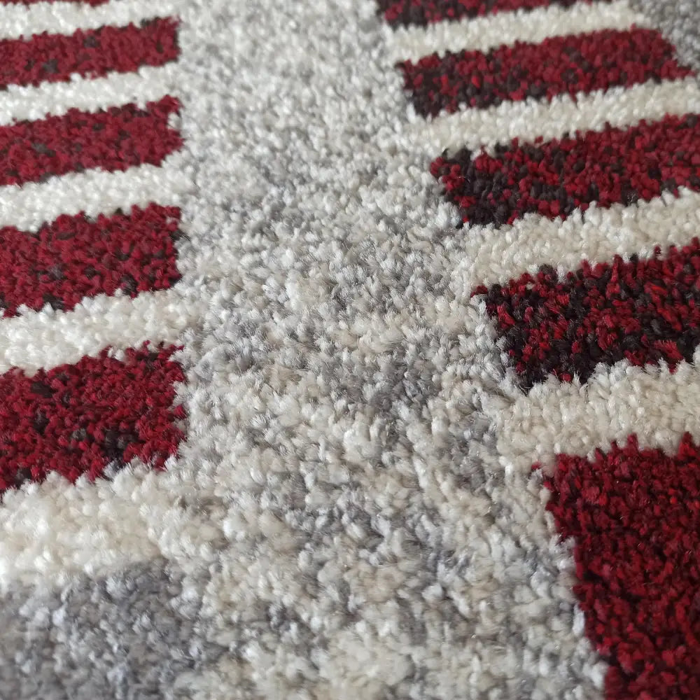 Tepe Otto-teppe i grått og rødt, nærbilde som fremhever tykkvevd tekstur og geometriske fargedetaljer.