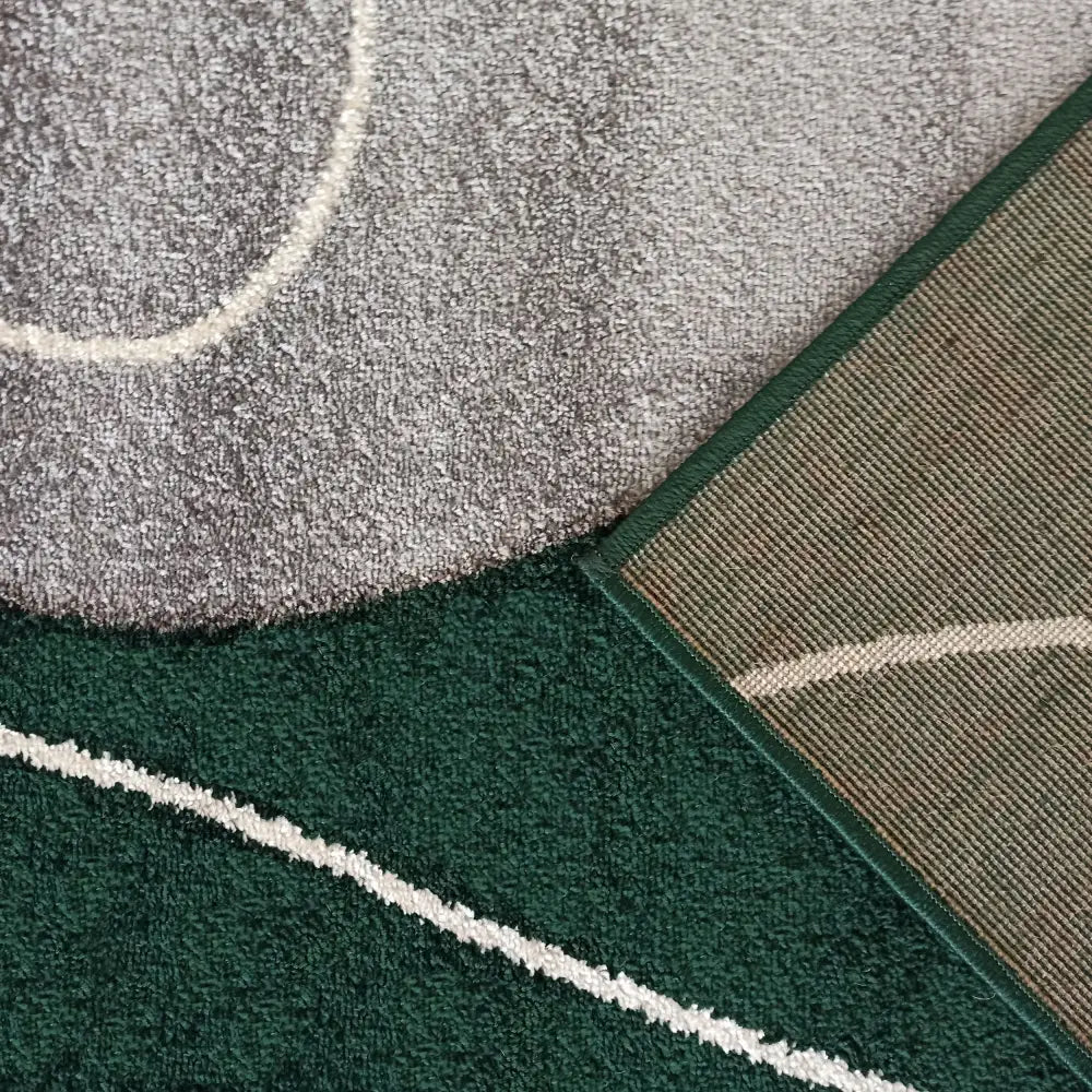 Tepe Otto teppe i grått og grønt, nærbilde av overside og hjørne med synlig bakside og hvite linjer.