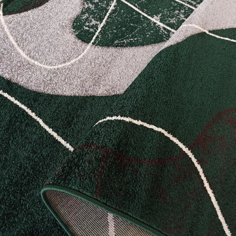 Tepe Otto teppe i grå og grønn, nærbilde av abstrakt mønster med synlig underside i bøyd hjørne.