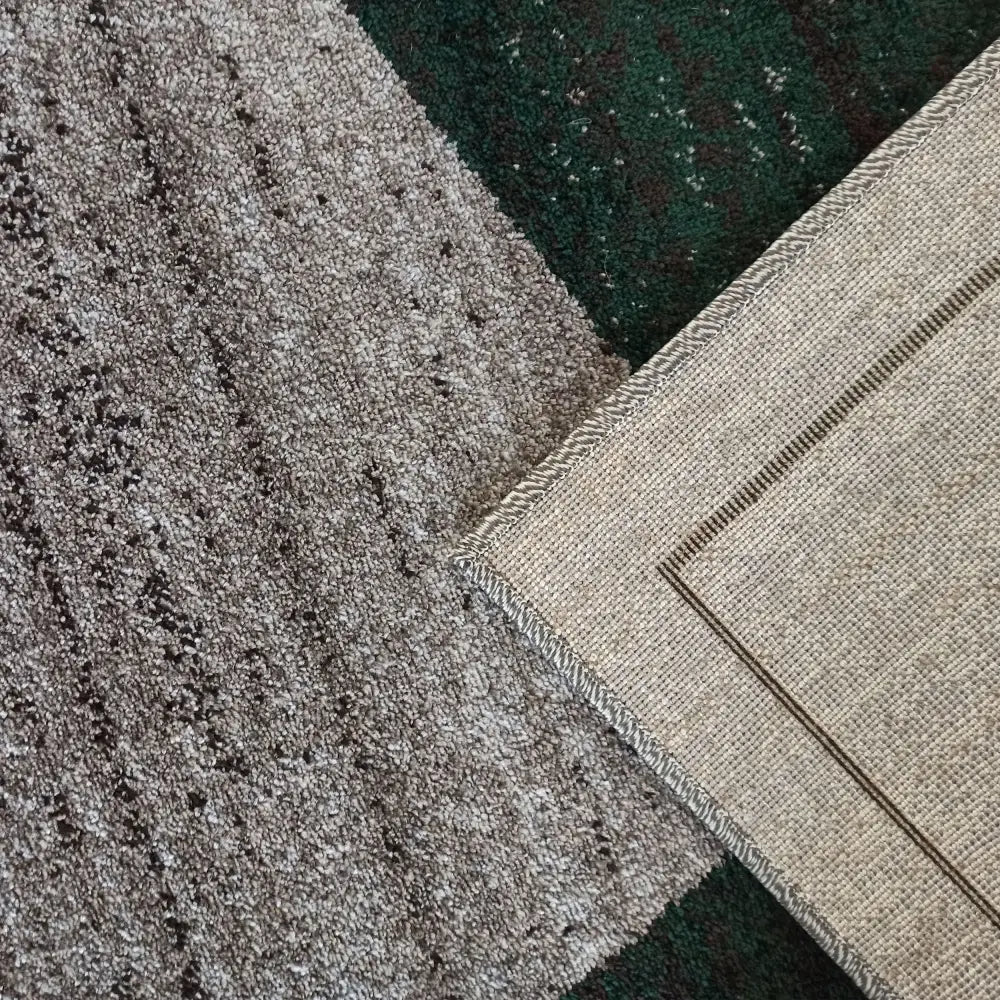 Tepe Otto-teppe i grått og grønt, nærbilde av brettet hjørne som avslører beige bakside og kantforsterkning.