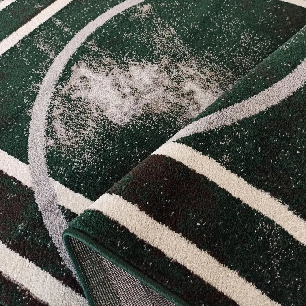 Tepe Otto 07 teppe i mørkegrønn, nærbilde av geometrisk mønster og tekstur med brettet hjørne.