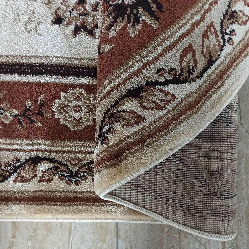 Tepe Oval teppe i brun, nærbilde av både overside og underside med blomstrete og kremfargede detaljer.