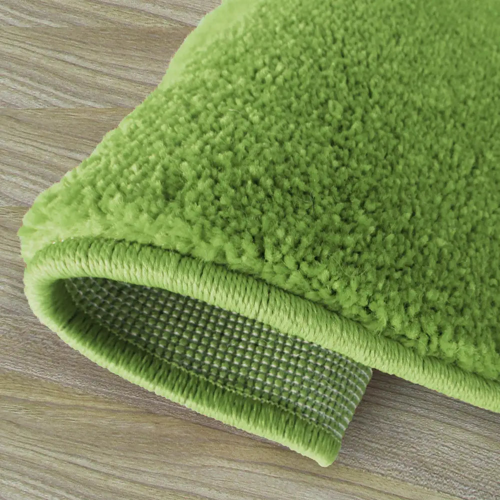 Tepe Portofino Rund grønt teppe, kort lugg og rutete sklisikker underside, sett skrått mot tregulv.