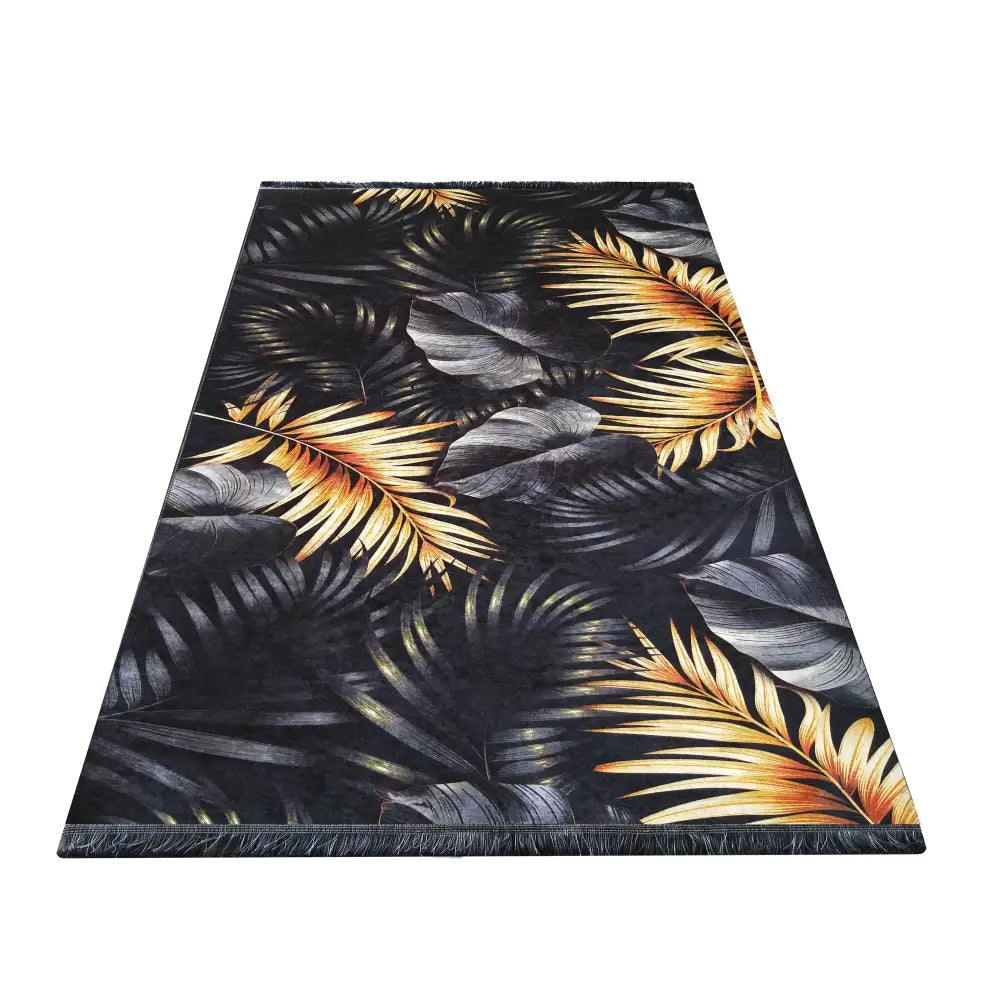 Tepe Premium svart og gull, teppe med tropisk bladmønster, frynser synlige i forgrunnen, skrå oversiktsvinkel.