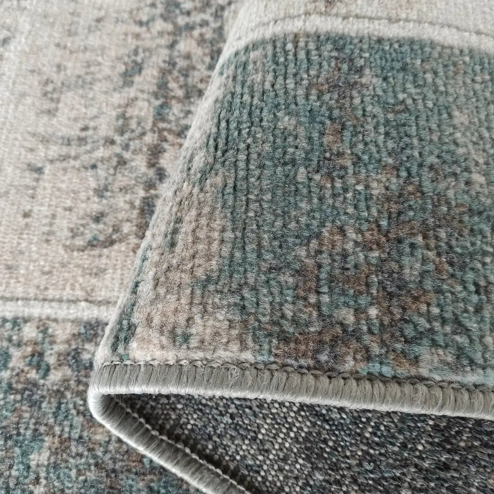 Tepe Roxanne teppe 160 x 220 cm, nærbilde av brettet hjørne med detaljert vevmønster og overlocket kant.