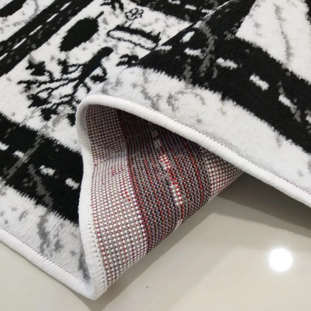 Tepe Soho 10 teppe i hvitt og svart, nærbilde av mønster og oppbrettet hjørne som viser rutete underside.