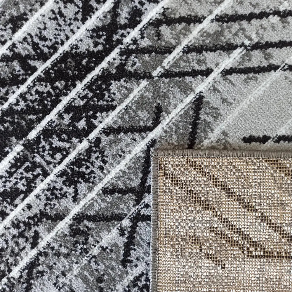 Tepe Soho 14 grått teppe, nærbilde av diagonalt mønster og brettet hjørne som viser vevd bakside.