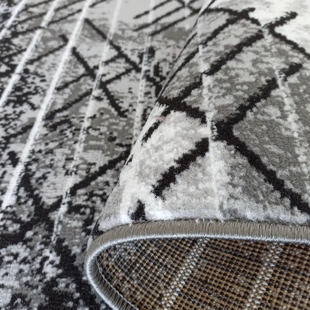 Tepe Soho 14 grått teppe, nærbilde av geometrisk mønster, synlig tekstur, kant og underside.