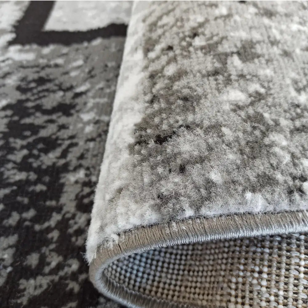 Tepe Soho grått teppe, nærbilde av tykk, myk luv i gråtoner med synlige kanter og bakside.