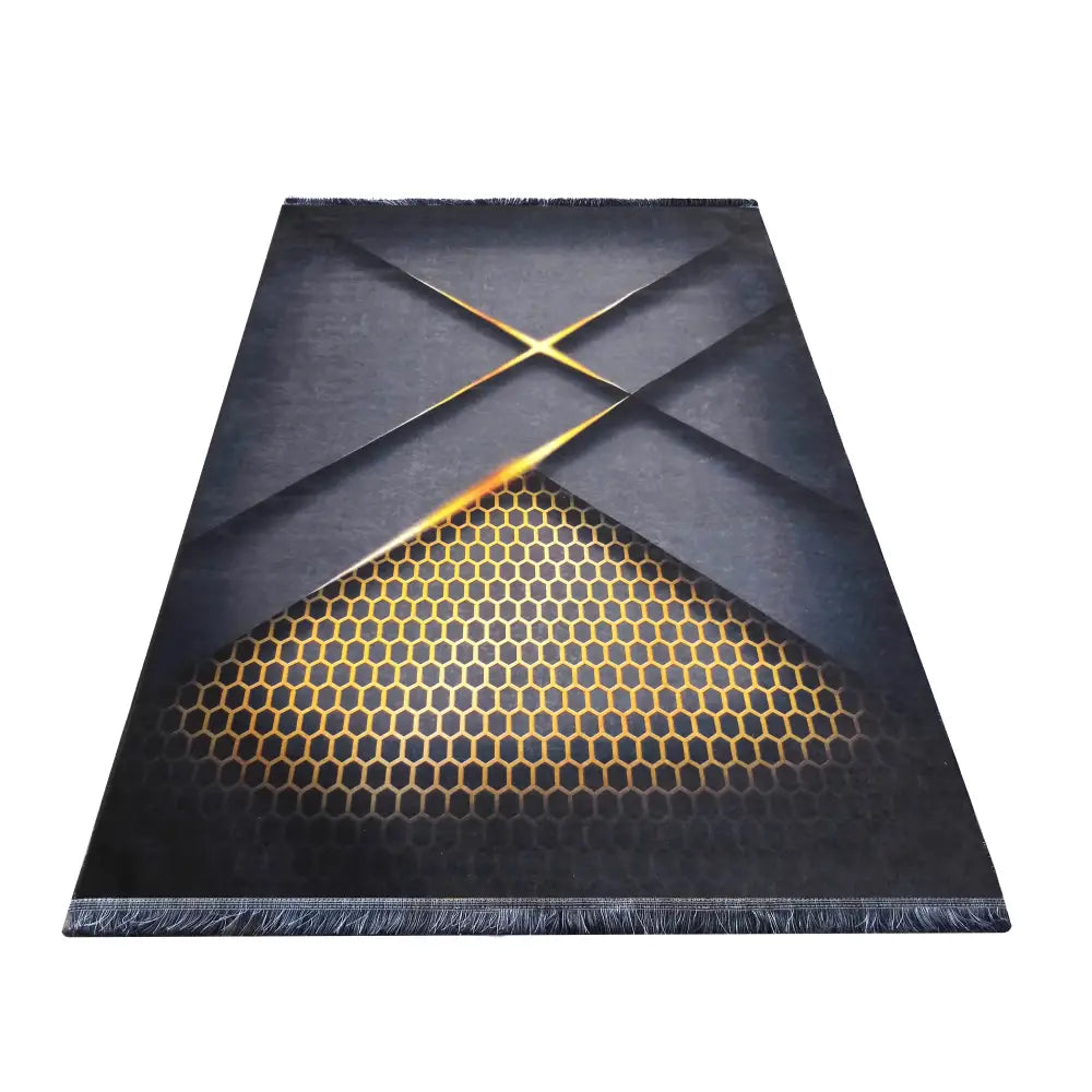 Tepe svart og gull teppe, sett ovenfra, med geometrisk honeycomb-mønster i gult og svart på mørkegrå bakgrunn.