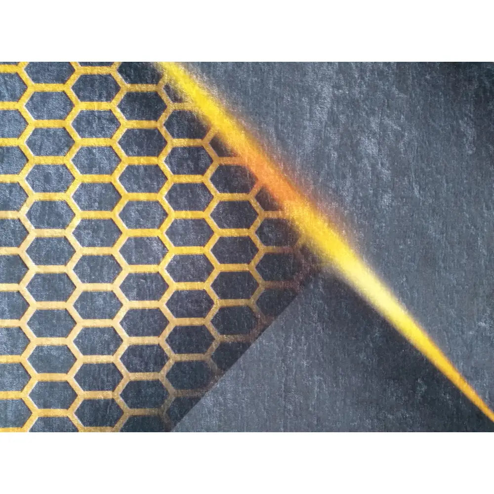 Tepe svart og gull teppe, nærbilde av gult bikubemønster og diagonal gul stripe på mørk bakgrunn.