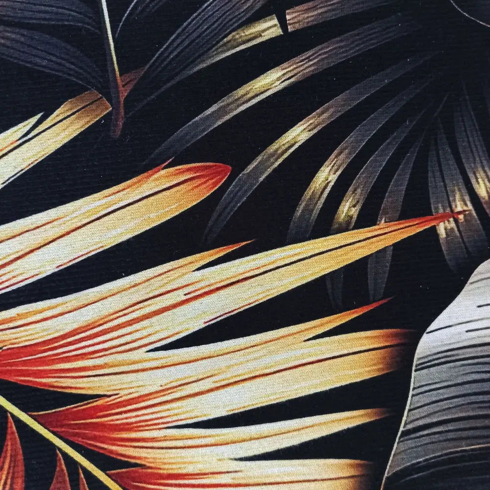 Tepe svart og gull, detaljert nærbilde av tekstil med fargerikt bladmotiv på svart bakgrunn, synlig stoffstruktur.
