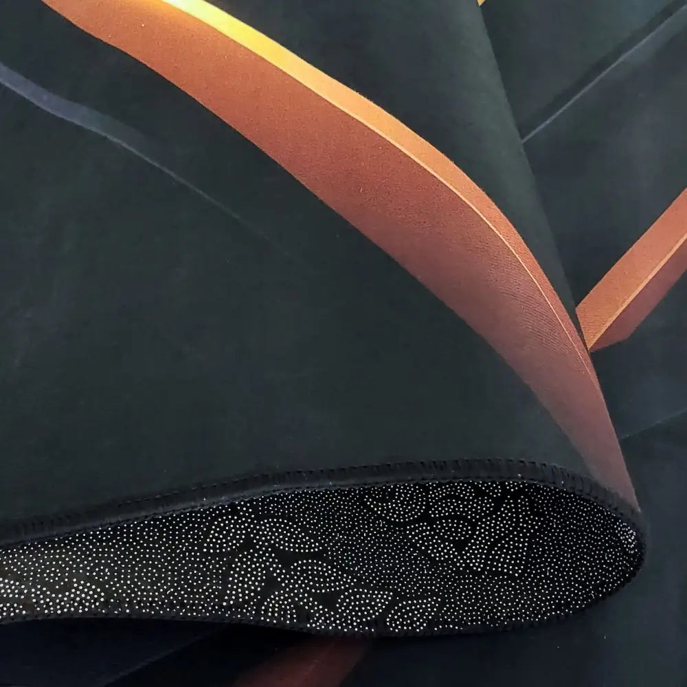 Svart og gull Tepe-teppe, nærbilde av stoff med oransje skrå striper og underside med hvite prikker.