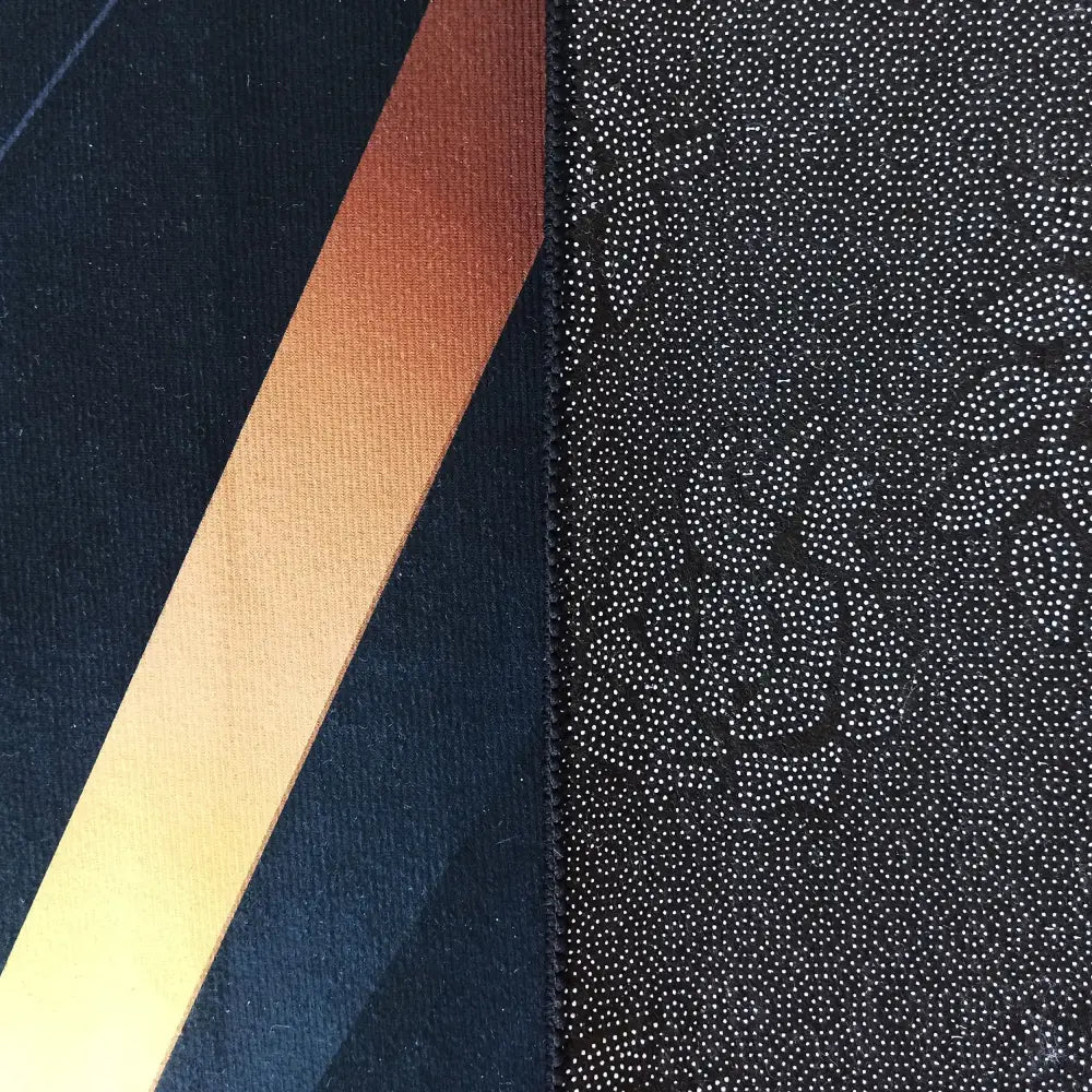 Tepe svart og gull teppe, nærbilde av blå og oransje felt samt svart tekstil med hvite prikker og blomster.