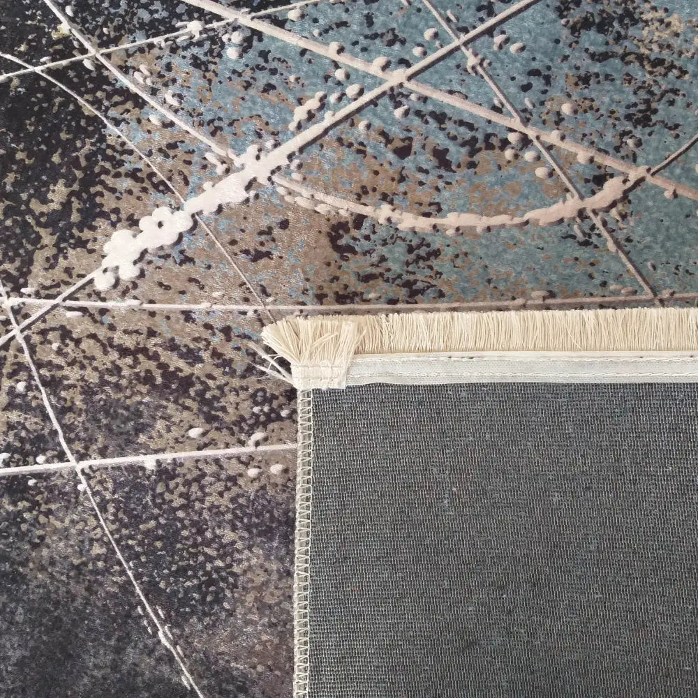 Teppet "Nytt 200S", nærbilde av hjørne med lyse frynser, synlig blått og beige abstrakt mønster.