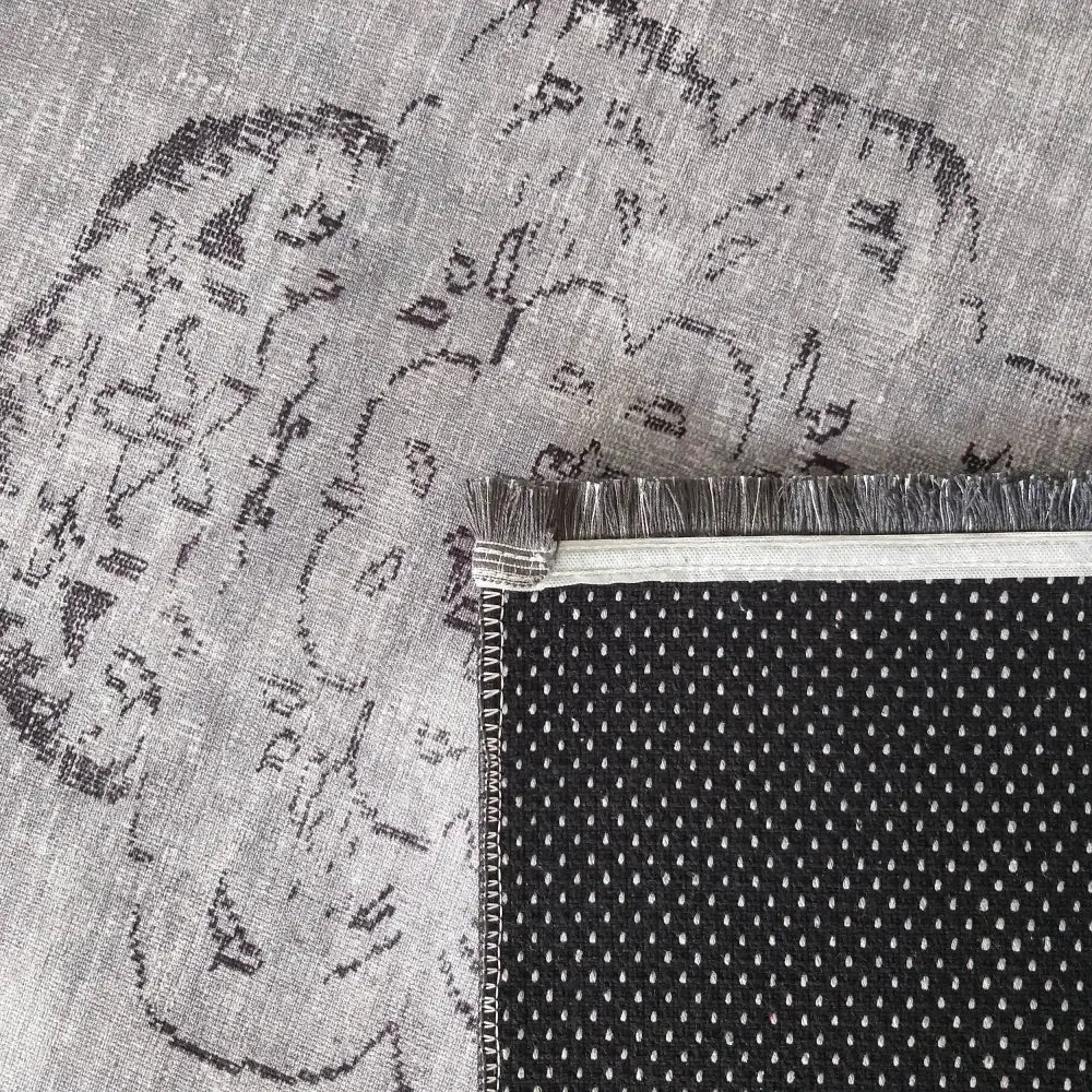 Tepe Vintage teppe i grått, nærbilde av brettet hjørne med sort sklisikker underside, hvite prikker og frynsekant.