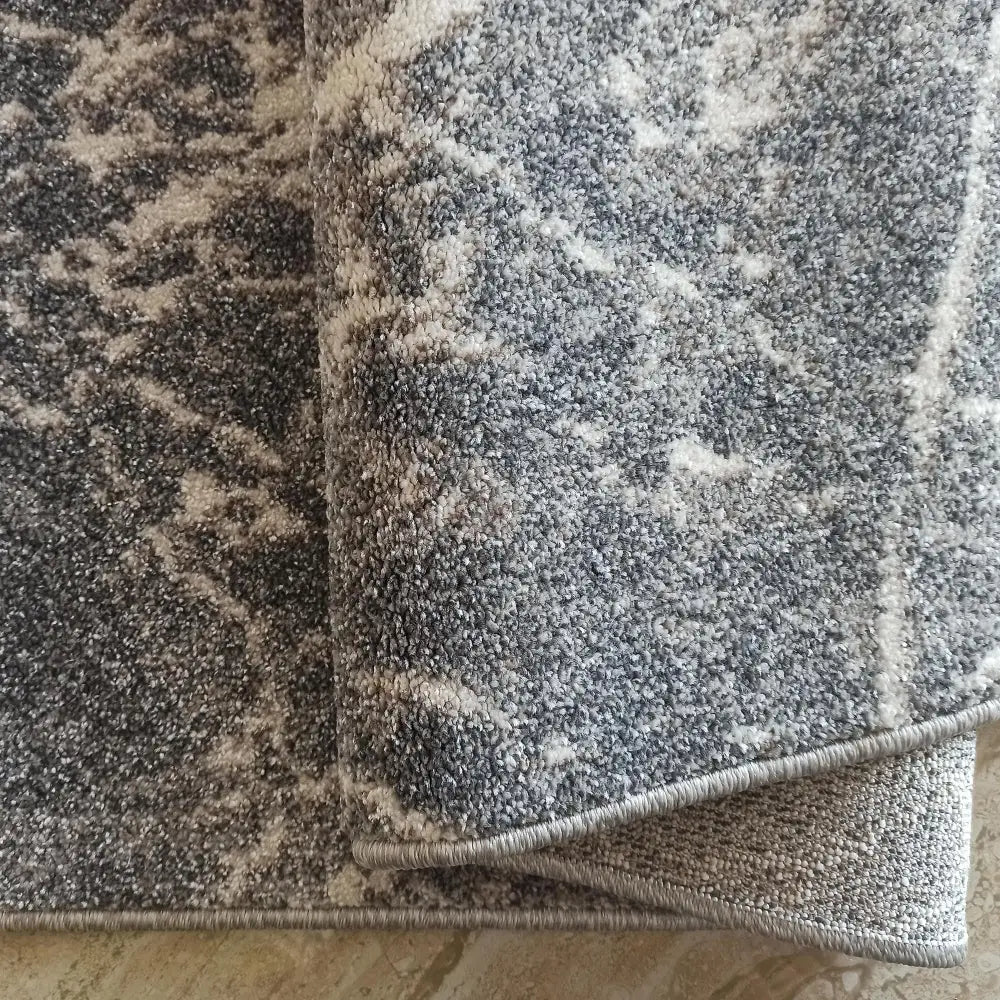 Tepe Vista 07 grå teppe, nærbilde som viser tettvevd struktur, beige detaljer og brettet kant.