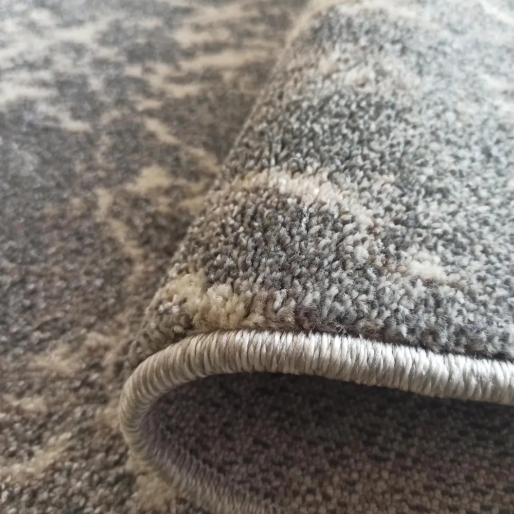 Tepe Vista 07 teppe i grå og beige, nærbilde som fremhever kantsøm, tykkelse og myk tekstur.